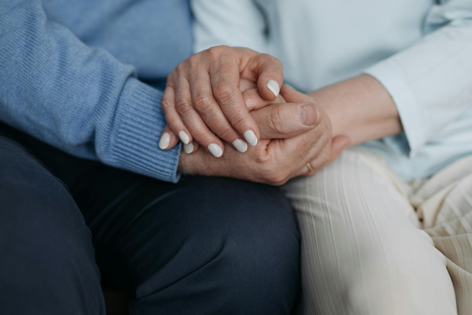 Two pairs of hands clasped together