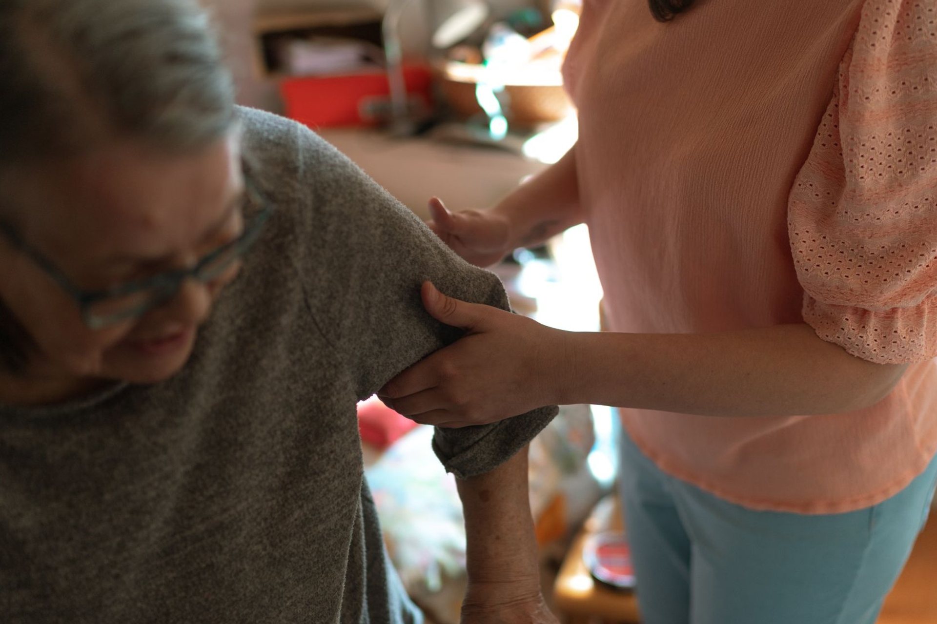 Caregiver helping an older woman into her sweater