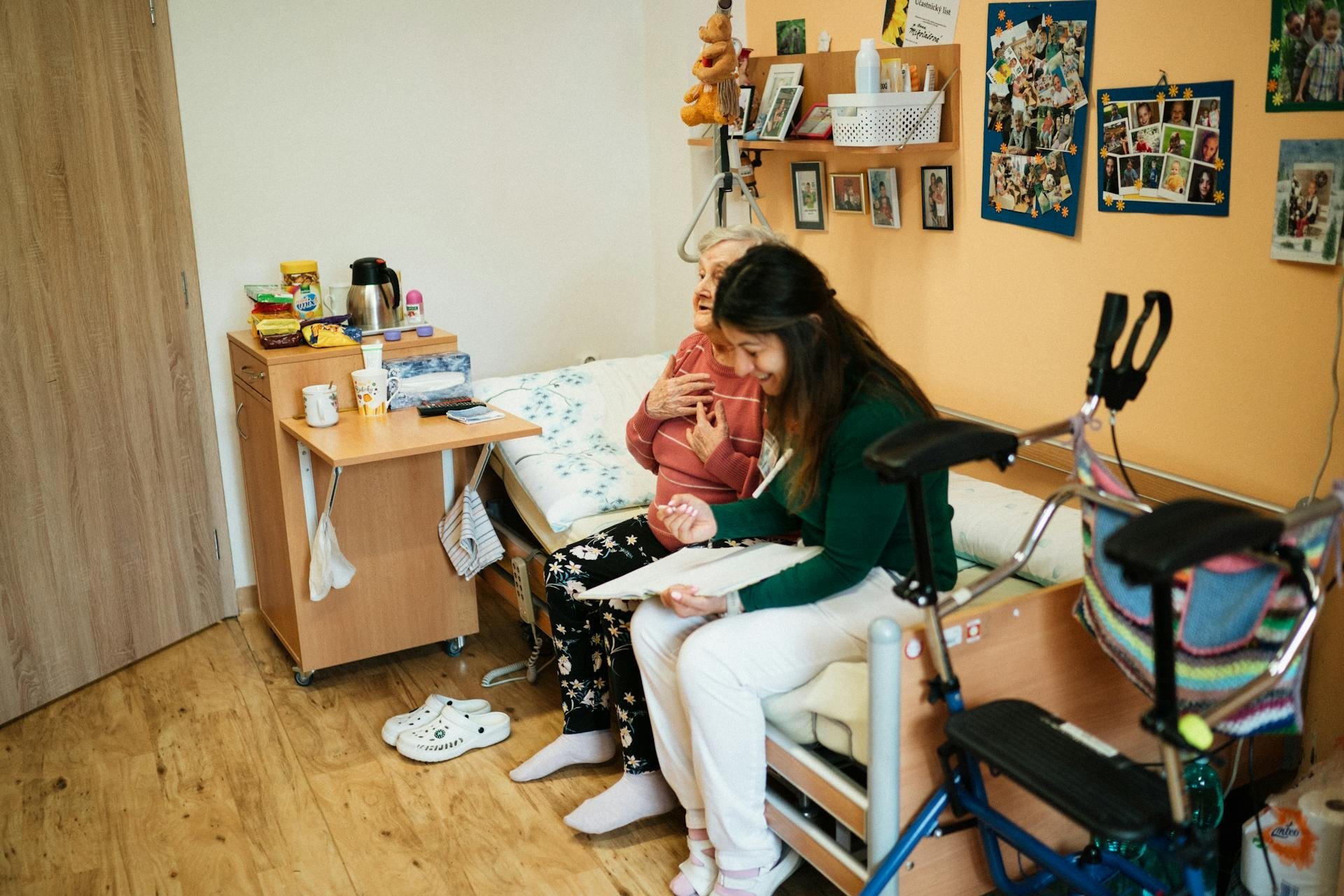 Caregiver reading beside an older woman at her bedside
