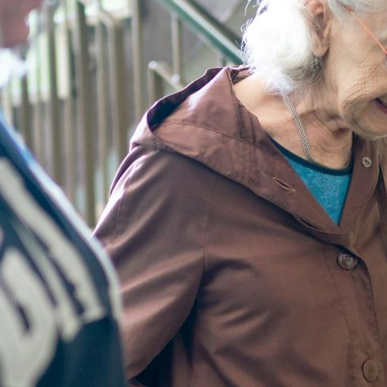 An older woman steadying herself on the stair rail